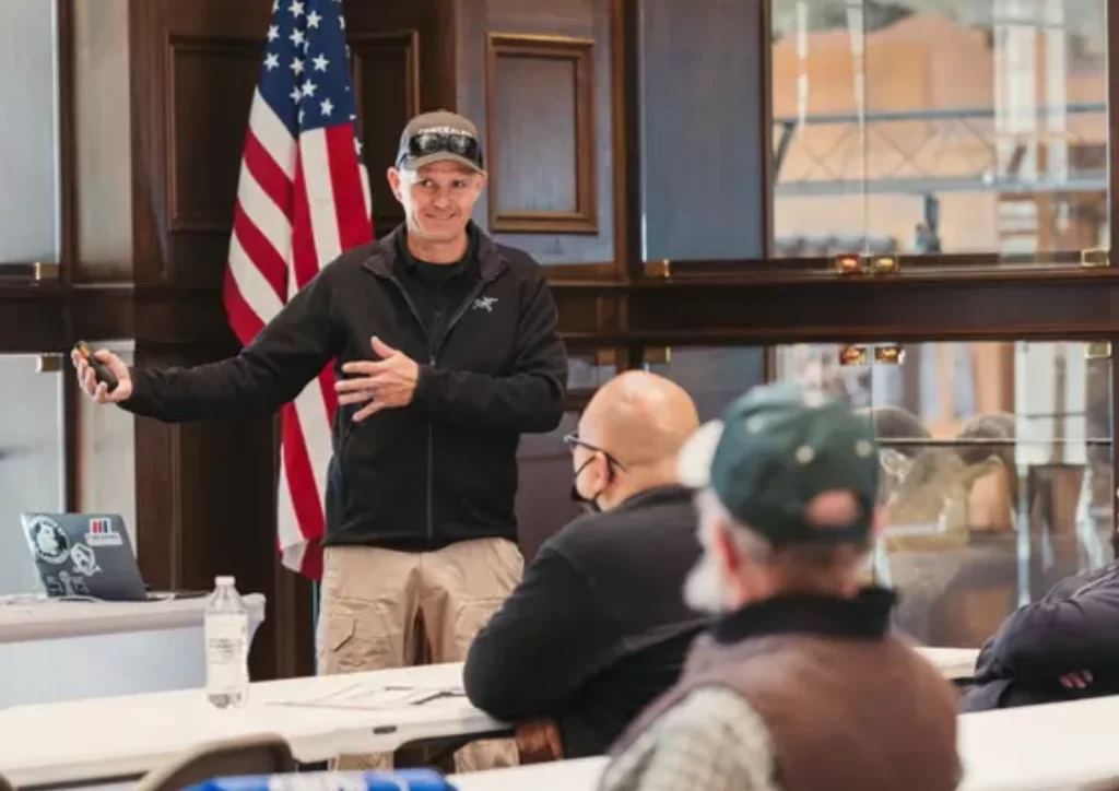 firearms instructor teaches pistol safety standing at the front of a classroom